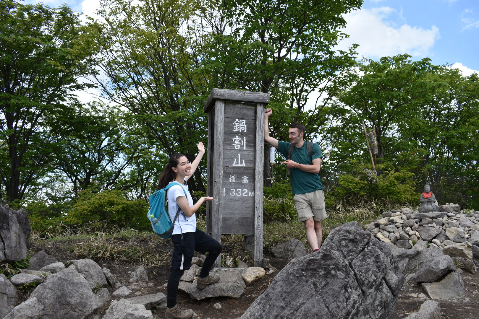 Two hikers at the Nabewariyama summit signpost