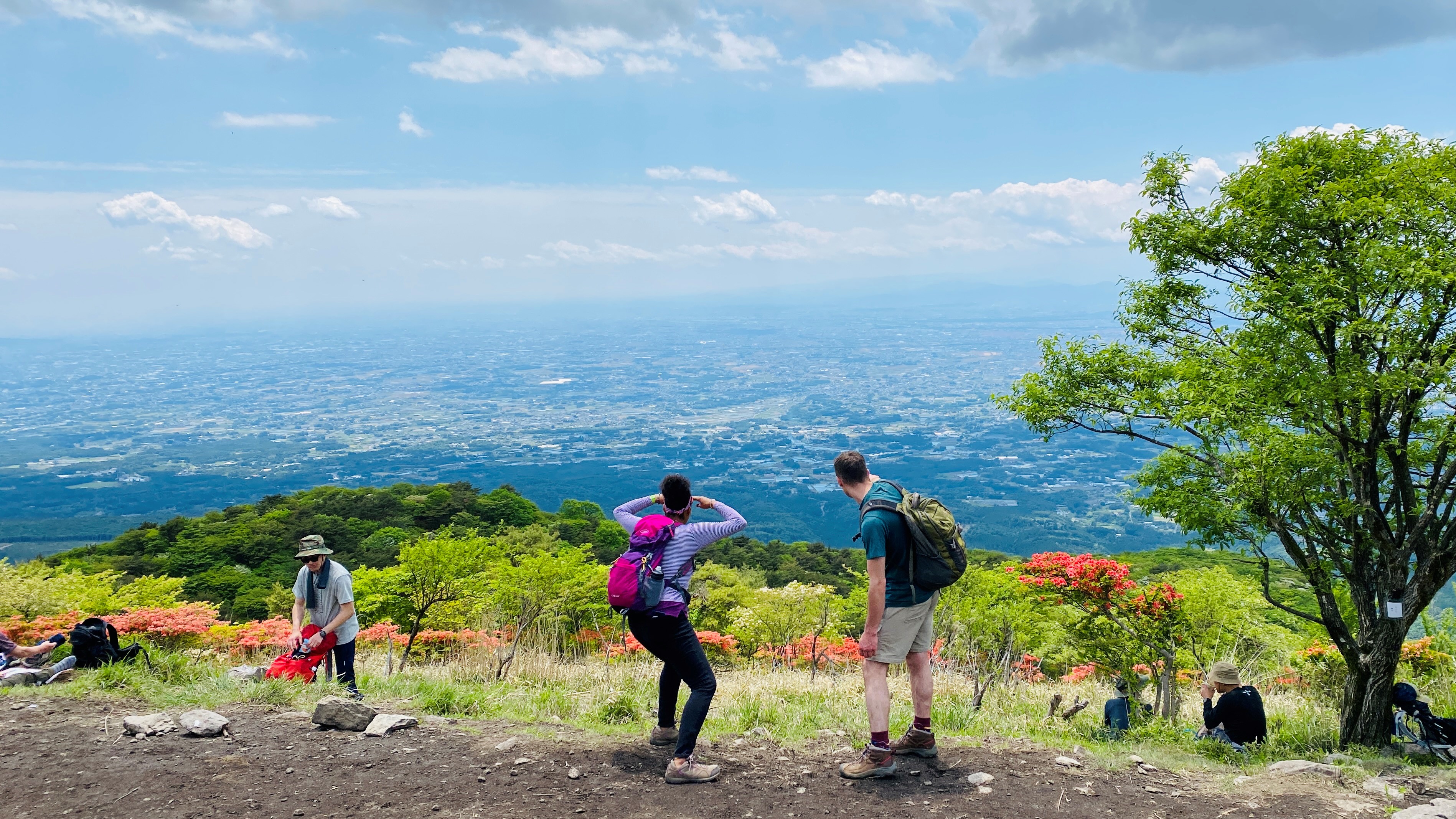 Enthusiastic hikers looking out at view of cityscape from Nabewari mountain summit