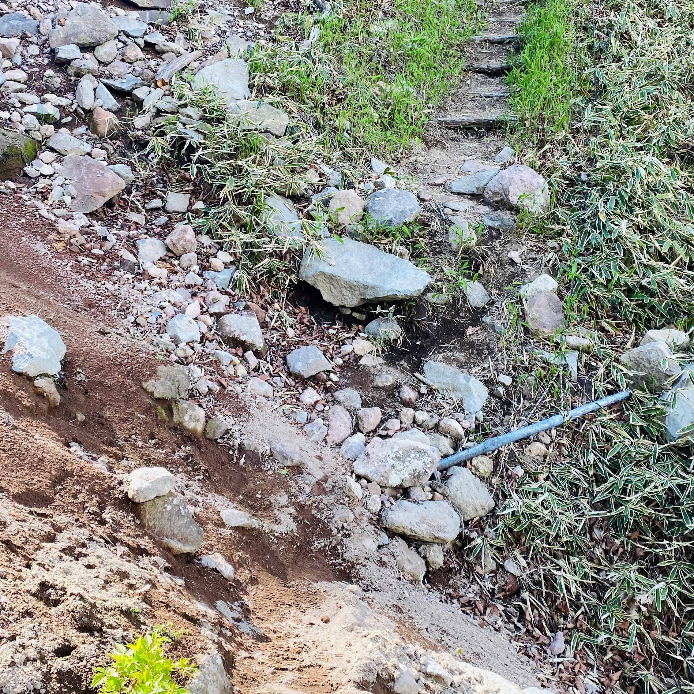 a hiking trail broken up slightly by rocks and sand from a landslide