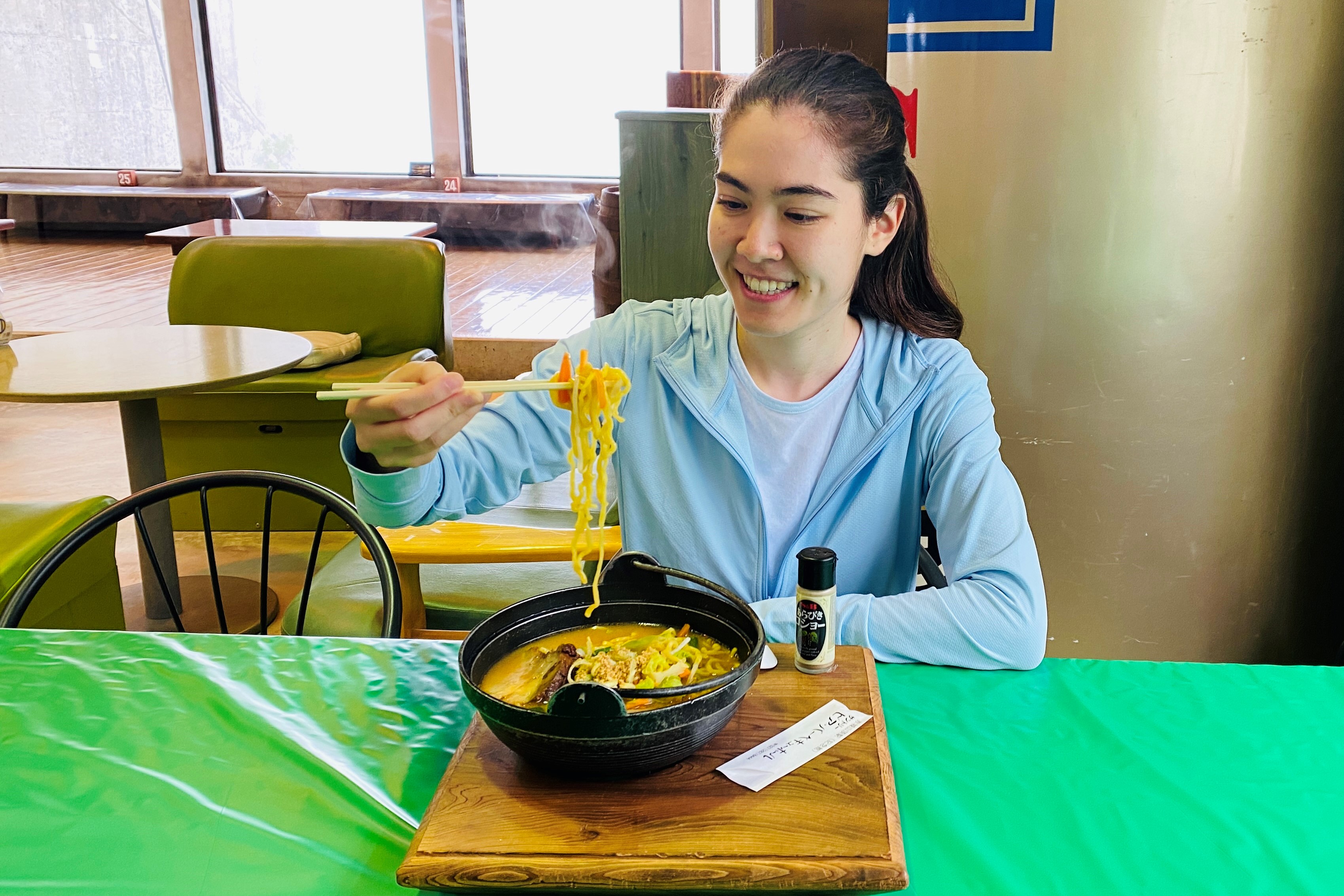 woman eating ramen noodle soup inside a restaurant