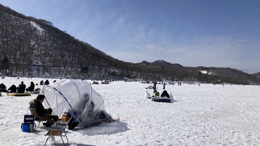 People ice-fishing in tents on a frozen lake