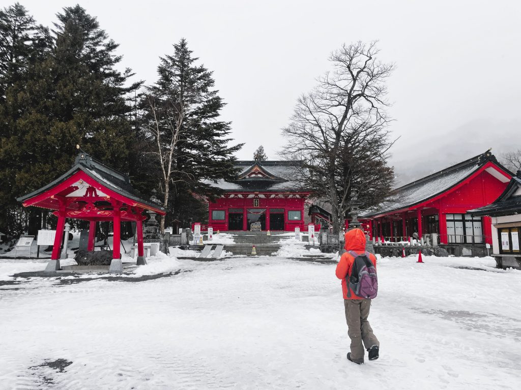 Person walking towards bright red Akagi Shrine